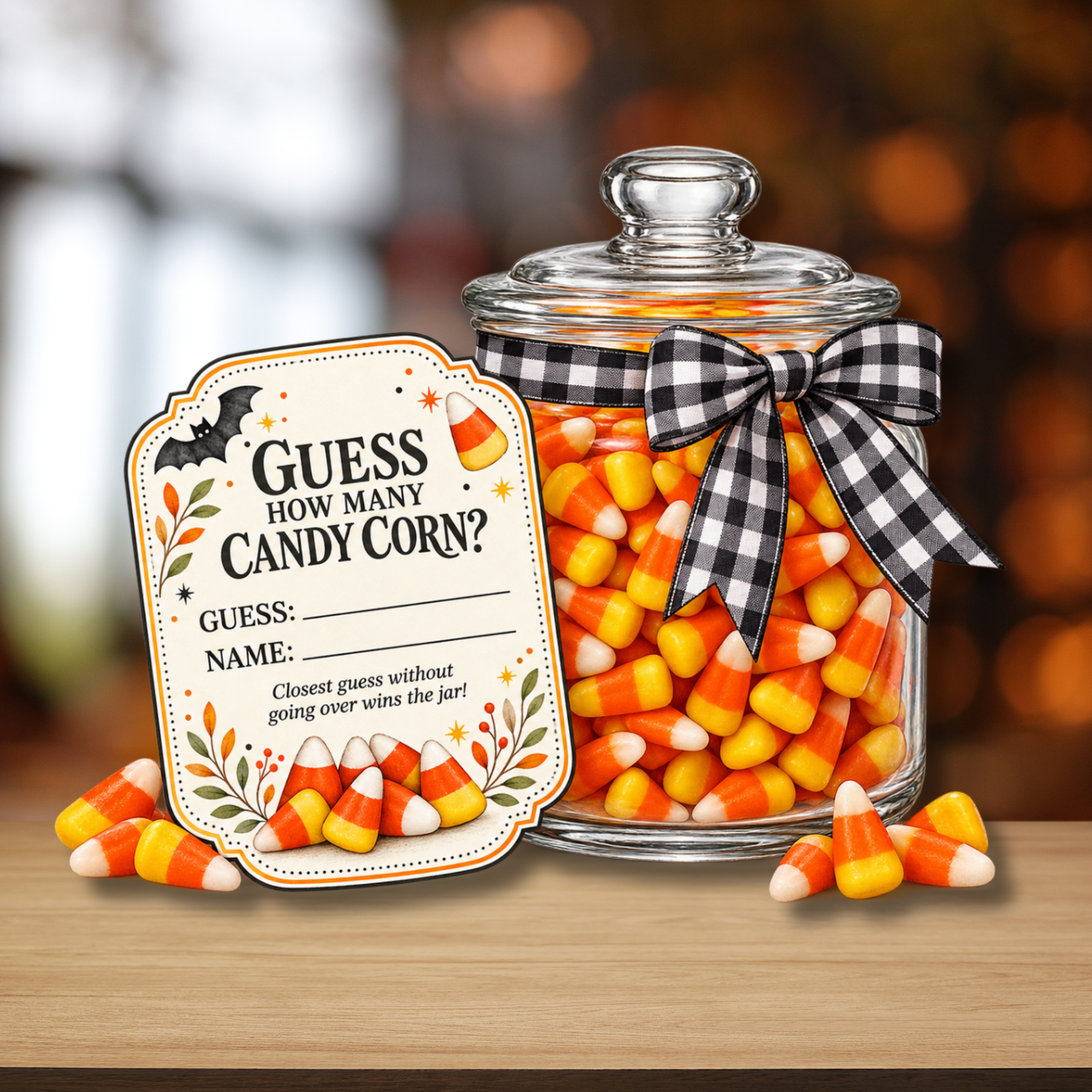 A clear glass jar filled with candy corn, tied with a black-and-white gingham ribbon, sits on a wooden surface with a matching decorative tag in front. The tag reads, 'GUESS HOW MANY CANDY CORN?' and includes Halloween-themed illustrations.