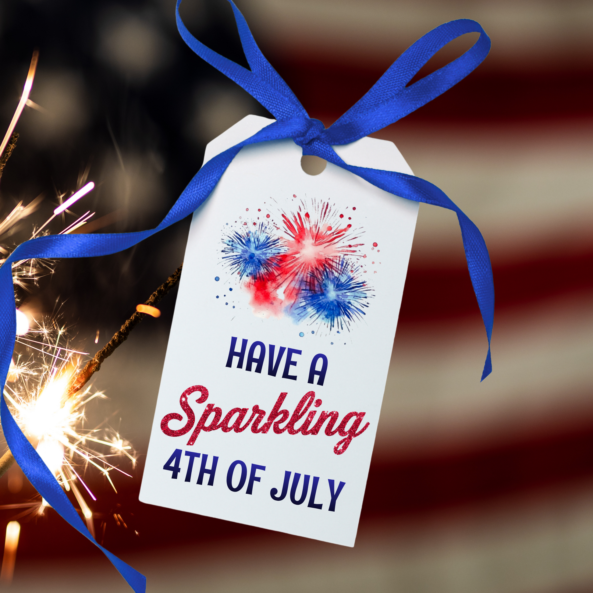 Gift tag with 'Have a Sparkling 4th of July' text and blue ribbon, with a blurred background of fireworks.